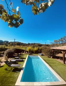 a swimming pool in a yard with chairs and a gazebo at Bastide provençale avec piscine in Cotignac
