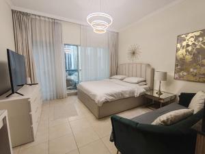 Un dormitorio con una cama, un televisor y un sofá. en Burj Al Nujoom Downtown Dubai Mall & Burj Khalifa, en Dubái