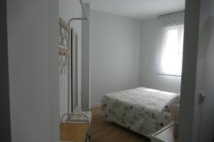 ein kleines Schlafzimmer mit einem Bett und einem Fenster in der Unterkunft Apartamento Fama in Cáceres