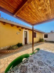 a patio with a green chair under a wooden roof at Le casette di Simona in Lampedusa
