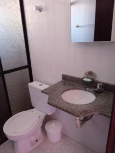 a bathroom with a white toilet and a sink at Edificio Residencial Vista Praia in Mongaguá