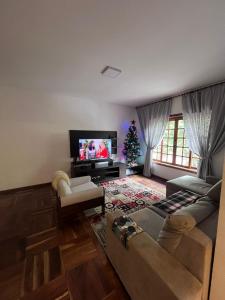 a living room with a couch and a christmas tree at Charmoso Duplex Rubi in Campos do Jordão