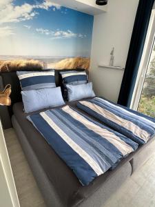 a bed with blue and white striped sheets and pillows at Sylt-Apartment in Hannover