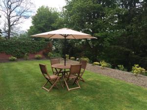 stół i krzesła pod parasolem na trawniku w obiekcie Mansfield House Hotel w mieście Hawick