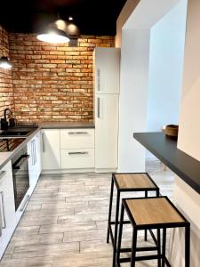 a kitchen with white cabinets and a brick wall at Apartament Loft Centrum in Częstochowa
