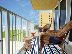 un porche avec des chaises en osier et des vases sur un balcon dans l'établissement Stylish Oceanfront Corner Condo - Steps to Beach & Flagler Ave Fun, à Chicken Island