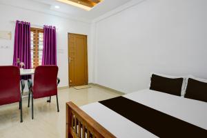 a bedroom with a bed and two chairs and a desk at Hotel O Pilappilly Apartments in Kakkanad
