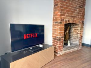 a television on a stand next to a brick fireplace at 4 Bed Home In Central Maldon in Maldon