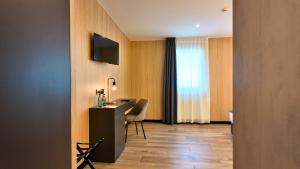 a hotel room with a desk and a television on a wall at Hotel Focus in Pas de la Casa