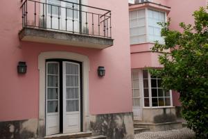 um edifício cor-de-rosa com uma porta branca e uma varanda em António Bastos 57 em Santarém