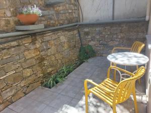 a patio with two chairs and a table and a stone wall at Samos Cozy Apartment II in Samos