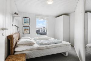 een witte slaapkamer met een bed en een raam bij LN1972-Hjorring-Hyttefadet-13 in Hjørring