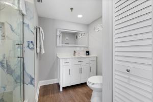 a white bathroom with a toilet and a shower at Oceanfront Beachside Condo - Pool, Beach, & Views in Chicken Island +19 photos