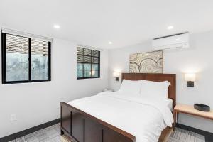 a white bedroom with a large bed and two windows at Sunnyside Studio on Green Lake in Seattle