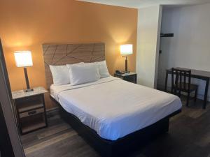 a bedroom with a bed with two lamps and a chair at Howard Johnson by Wyndham Malden Boston Area in Malden