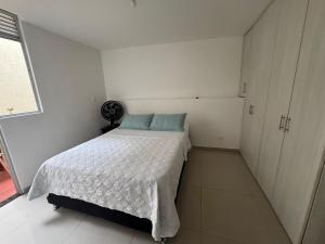 a small white bedroom with a bed and a window at Apartaestudio en a Milla de oro, restaurantes, Centros comerciales, clínica Keralty in Ibagué +30 photos