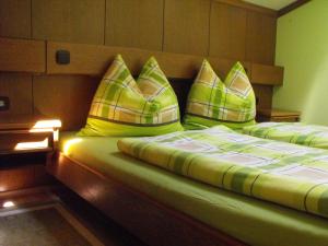 Una cama con almohadas verdes y amarillas. en Olympia Apartment en Latschach ober dem Faakersee