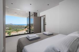 a bedroom with a large bed and a large window at Villa Trapezia Diamond in Kolymbia +24 photos