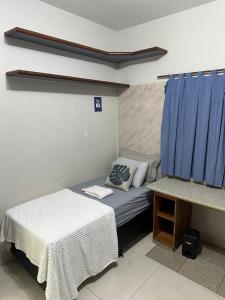 a bedroom with two beds and a blue curtain at Apartamento localizado no centro da cidade in Primavera do Leste +6 photos