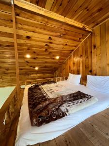 a large bed in a room with wooden walls at Attic Cottage - Country Club Resorts Balakot in Bālākot