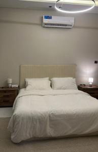 a bedroom with a white bed with a air conditioner on the wall at شقة الزمرد in Jeddah
