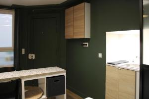 a kitchen with green walls and a counter top at Studio 2 steps from the Musée Grévin in Paris