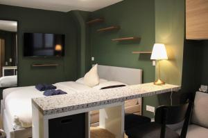 a room with a bed and a desk with a television at Studio 2 steps from the Musée Grévin in Paris