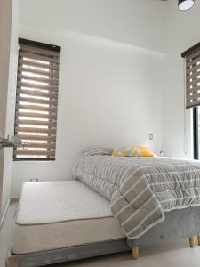 a bed in a bedroom with white walls and windows at Avemaría! in Puente Nacional +25 photos