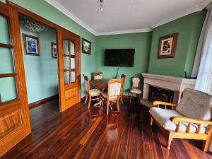 a living room with green walls and a table and chairs at Casa Villadam in Ribadesella