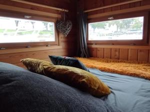 a bedroom with two windows and a bed with pillows at La Toue Charme - Bateau traditionnel de la Loire in Angers
