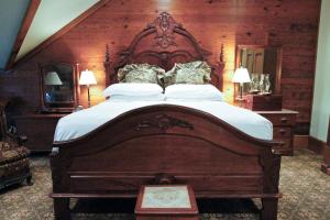 a bedroom with a large bed with a wooden headboard at The Chaska House & Cottages in Waxahachie