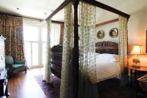 a bedroom with a canopy bed with curtains at The Chaska House & Cottages in Waxahachie