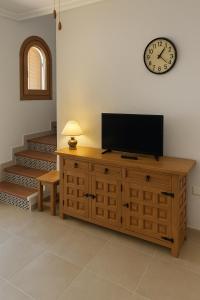 a television on a dresser with a clock on the wall at CasasQuesada in Ciudad Quesada