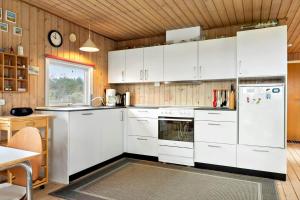 a kitchen with white appliances and a wooden wall at LN1957-Hirtshals-Fyrreklitten-4 in Hirtshals