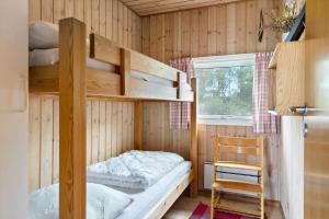a bedroom with bunk beds and a chair and a window at LN1957-Hirtshals-Fyrreklitten-4 in Hirtshals