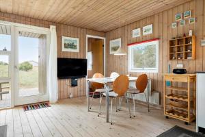 a dining room with a table and chairs and a television at LN1957-Hirtshals-Fyrreklitten-4 in Hirtshals