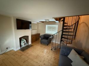 a living room with a staircase with a chair and a fireplace at 1 Top Locks Cottage in Burscough