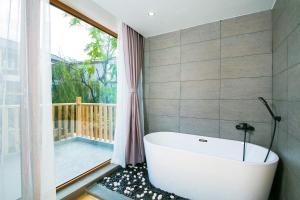 a bath tub in a bathroom with a balcony at Zhuzhi Light Luxury B&B in Lijiang
