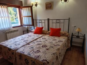 a bedroom with a bed with red pillows on it at Apartamentos Rurales Llagumelon in Villahormes