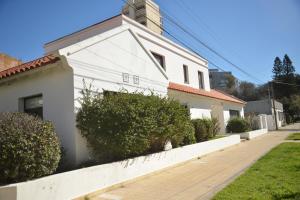 a white house with bushes next to a fence at Beach House AP in Miramar