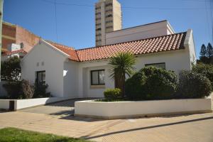 a white house with a palm tree in front of a building at Beach House AP in Miramar