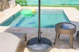 a pool with a table and a chair and an umbrella at Residencia Bambou HAVRE DE PAIX in Juan Dolio