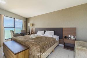 a hotel room with a large bed and a chair at Estúdio Vista Mar em Recife BCI1603 in Recife +9 photos
