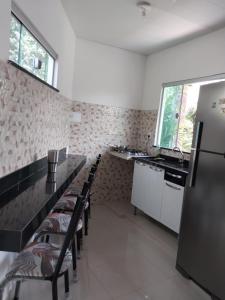 a kitchen with a long counter with chairs and a refrigerator at Cop 30 urban Amazon Paradise 5 bedrooms 7 beds in Ananindeua +3 photos