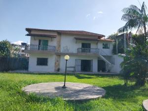 a white house with a palm tree in front of it at Cop 30 urban Amazon Paradise 5 bedrooms 7 beds in Ananindeua