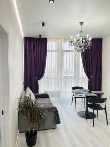 Schlafzimmer mit einem Bett und einem Tisch sowie lila Vorhängen in der Unterkunft Апартаменты с панорамным видом возле моря in Odessa