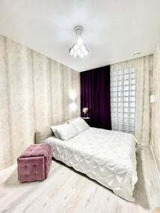 ein Schlafzimmer mit einem weißen Bett und einer rosa Ottomane in der Unterkunft Апартаменты с панорамным видом возле моря in Odessa