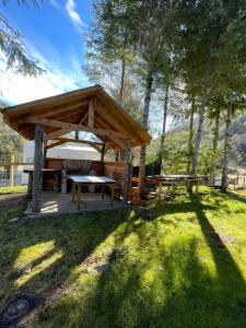 a wooden pavilion with a picnic table and a bench at Cabañas cordillera Rio Blanco in Reigolil