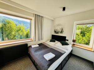 a bedroom with a bed and two large windows at Willa Makuchówka in Korbielów