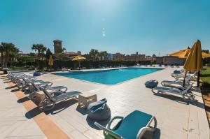 a swimming pool with lounge chairs and umbrellas at الفيروز in 6th Of October
